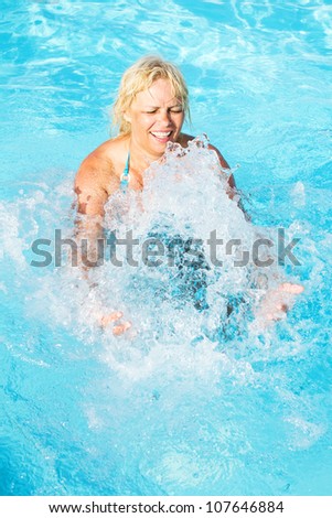middle-aged woman inserts her hands under the turbulent flow of water in the pool