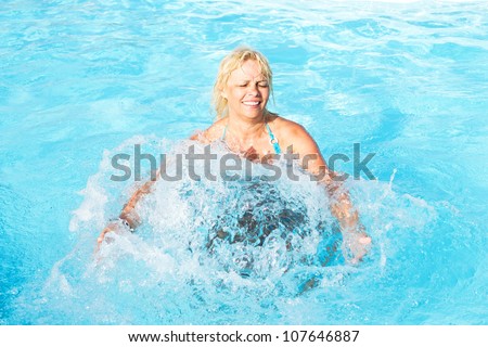 middle-aged woman bathed in swirling flow of water in the pool with blue water