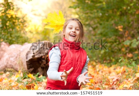 cute little girl catches a falling autumn leaf