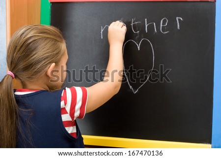 schoolgirl writes on the blackboard the word \