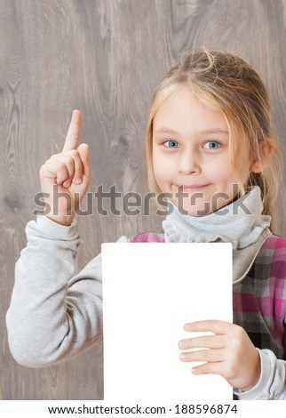 little girl holding a sheet of white paper and points finger up