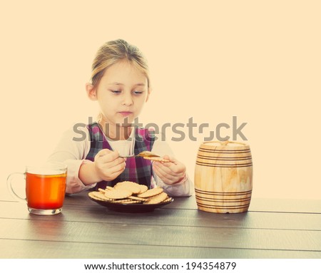 girl eats cookies with honey from a wooden keg