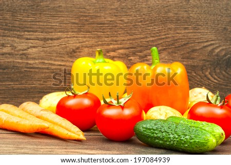 tomatoes, cucumbers, carrots and potatoes on wooden background