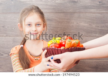 little girl takes hands basket with vegetables
