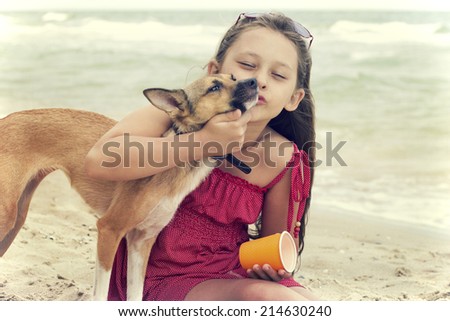 child hugging a puppy on the beach