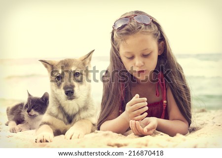 Child and puppy and kitten on a sandy beach