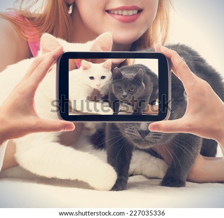 girl with two cats photographed on a smartphone