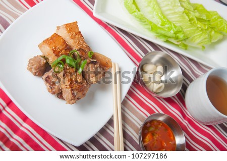 grilled pork wrapped with green leafy vegetables and fresh garlic