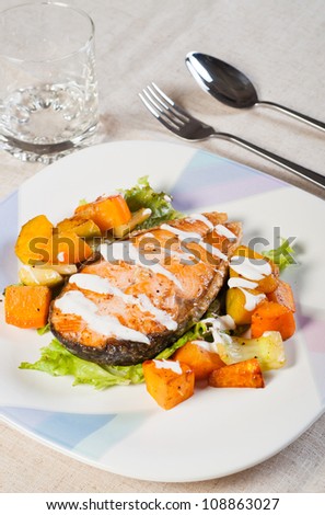 fried salmon on a garden salad and fresh buttered vegetables