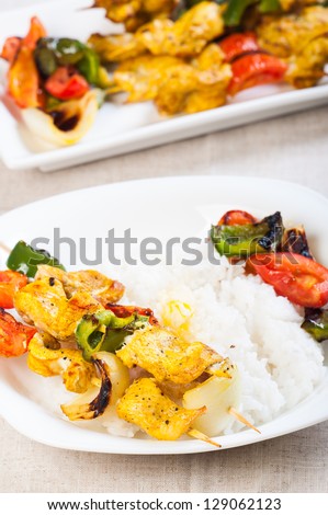 chicken kebab plated with buttered rice and vegetables on a side
