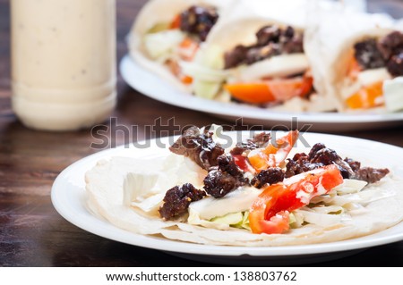 beef with tomatoes lettuce and onions drizzled with garlic sour cream wrapped in pita bread/beef shawarma