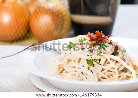 white sauce spaghetti topped with crispy bacon and parsley