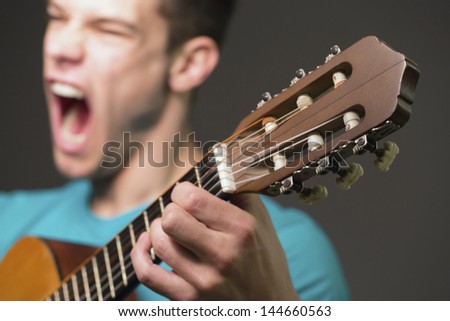 Young Guitar Player Performing Over Gray Background