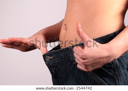 Lost Weight woman showing how much she has lost by putting on an old pair of jeans.