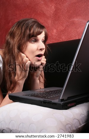 Shocking News a young woman looking shocked in front of her laptop on the couch.