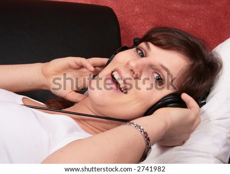 Relaxing Music a young fresh woman is listening to music on her couch and smiling.