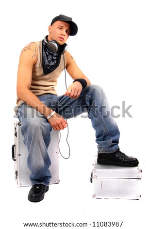  Young Man Sitting On Dj Cases With Headphones And Lots Of Tattoos