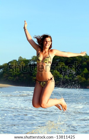 Pure Happiness A young woman at the beach in the water. Jumping for joy with a bikini. Ideal summer / vacation shot.