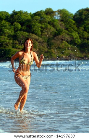 Running Beauty A young woman at the beach in the water. Jumping for joy with a bikini. Ideal summer / vacation shot.