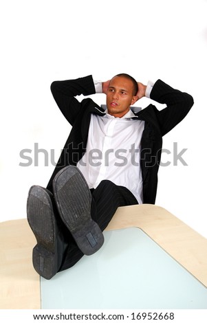 Relaxed Businessman A young satisfied businessman sitting by desk at office feet on table thinking. Isolated over white.