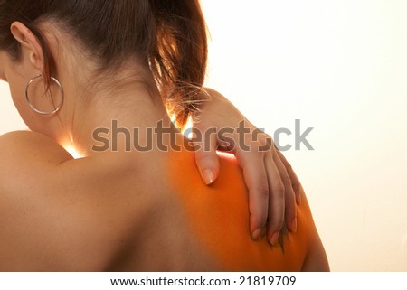 Severe Shoulder Pain A young woman holds her back in pain! The area on the shoulder is highlighted to symbolize the pain.