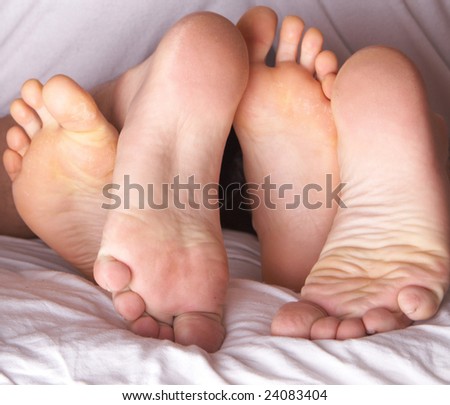 Four feet in a bed. A young couple is having fun.