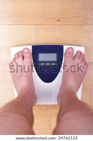 A scale with two feet of the person standing on it on a wooden floor. The scale display is empty.