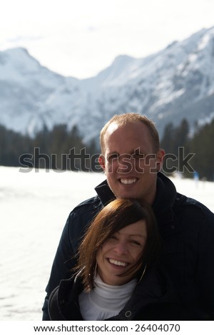A young couple outdoor in a winter setting. The couple is hugging each other.