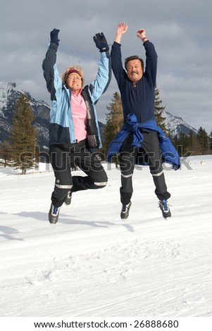 A senior couple outdoor in a winter setting. The couple jumps in the air. Slight motion bluriness is intend.