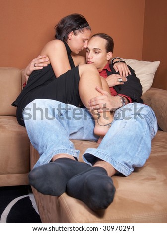 Young couple cuddling on a couch at home coming back from a party.