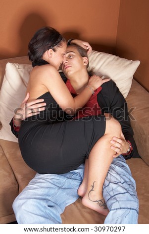 Young couple lying on couch at home. Cuddling after a party.