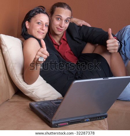 Young couple on the couch surfing the web with their laptop.