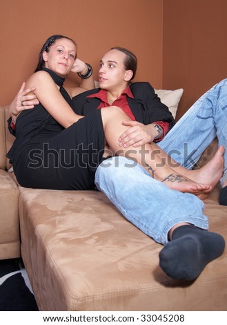 Young couple cuddling on a couch at home coming back from a party.