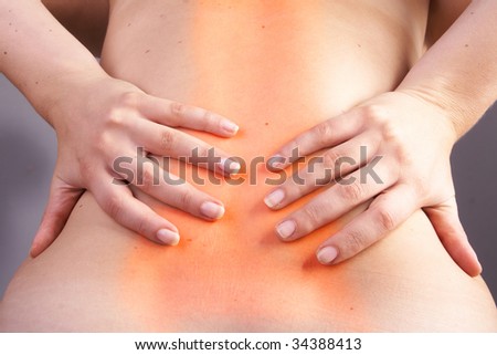 Young woman with sever back pain. She is holding her schoulder. Over gray background. The hurting area was saturated in red to symbolize the pain.