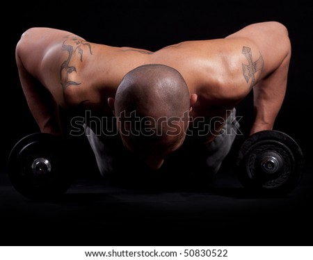 Young bald strong man is working out over black background.