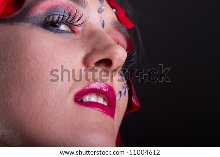 Young fresh woman with an extreme and glamorous makeup and roses on her face.
