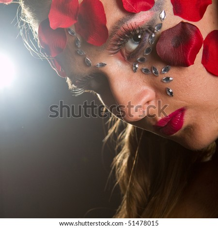 Young stylish fresh young model with an extreme red makeup and roses.