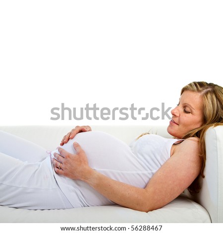 Young fresh pregnant woman lying on a stylish white couch over white background.