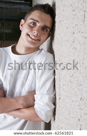 Young teenage boy leaning against a wall in anurban setting.