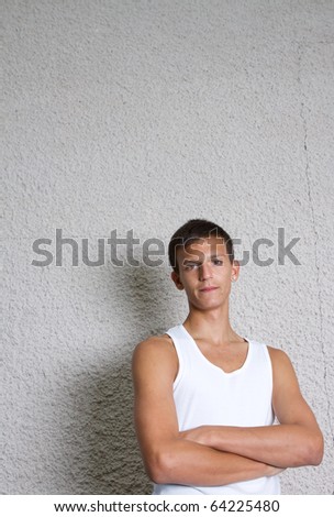 Young teenage boy leaning against a wall in anurban setting.