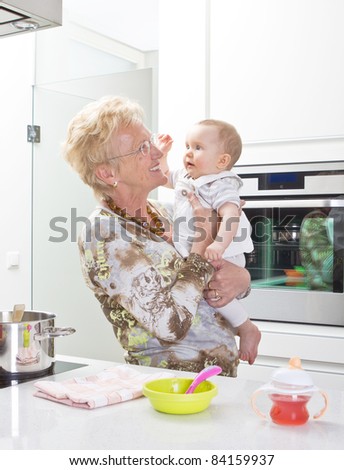Young mother with baby girl and the grandmother in a modern kitchen setting.