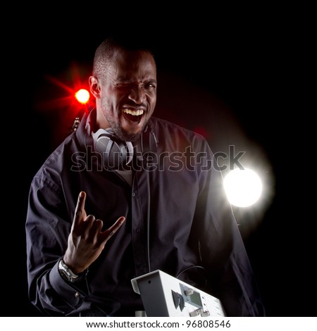 Young black man with a keyboard and headphones over black background.