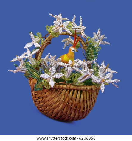The basket decorated by beads. Flowers are made of beads. The bird in the middle sits.