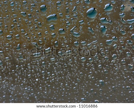 Drops of water on a smooth surface (glass). Small light drops. Focus on top.