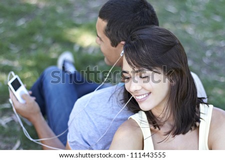 Young couple sharing and listening to music device