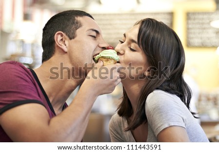 Attractive romantic couple sharing a cupcake in a coffee shop