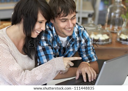 Attractive young couple smiling while pointing at laptop screen