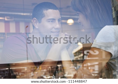 Attractive young romantic couple sitting inside coffee shop holding hands