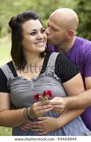 Man kissing lady with flower in hand