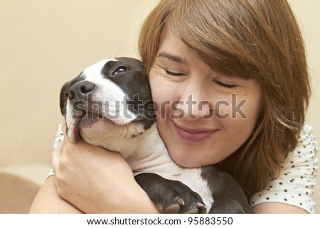 Young attractive female embracing her Pit Bull puppy